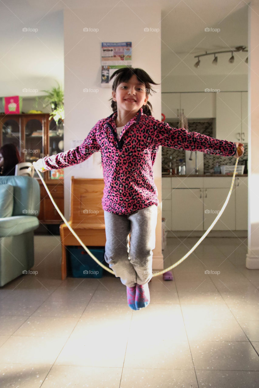 Cute little girl is jumping on a skipping rope