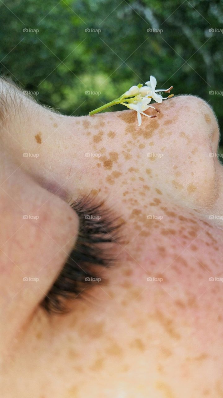 profile of girl with freckles with flower on her nose