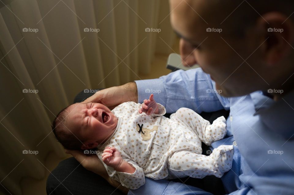 baby girl crying in dad's arms