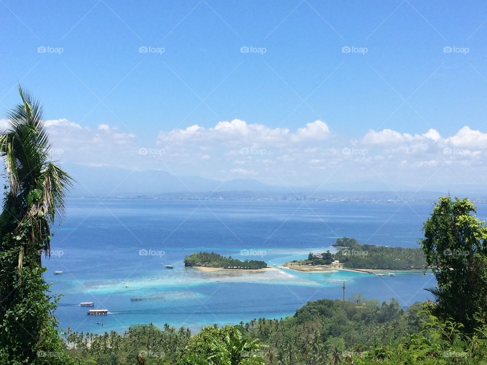 a very scenic  view of islands and sea  with a background of cityscape under a cloudy sunny day 