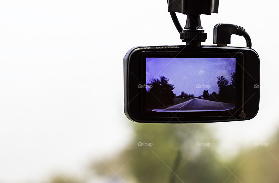 Picture road and tree on camera in car.