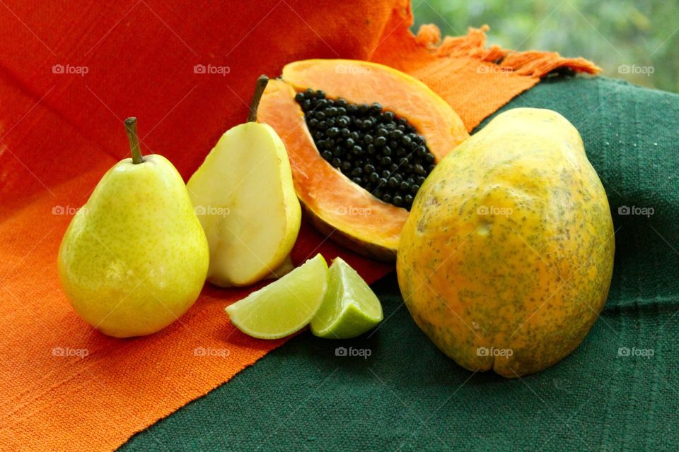 Papaya, pear and lemon on an orange and green background