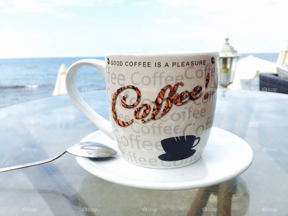 Coffee mug with the logo good coffee is a pleasure on a beach bar table