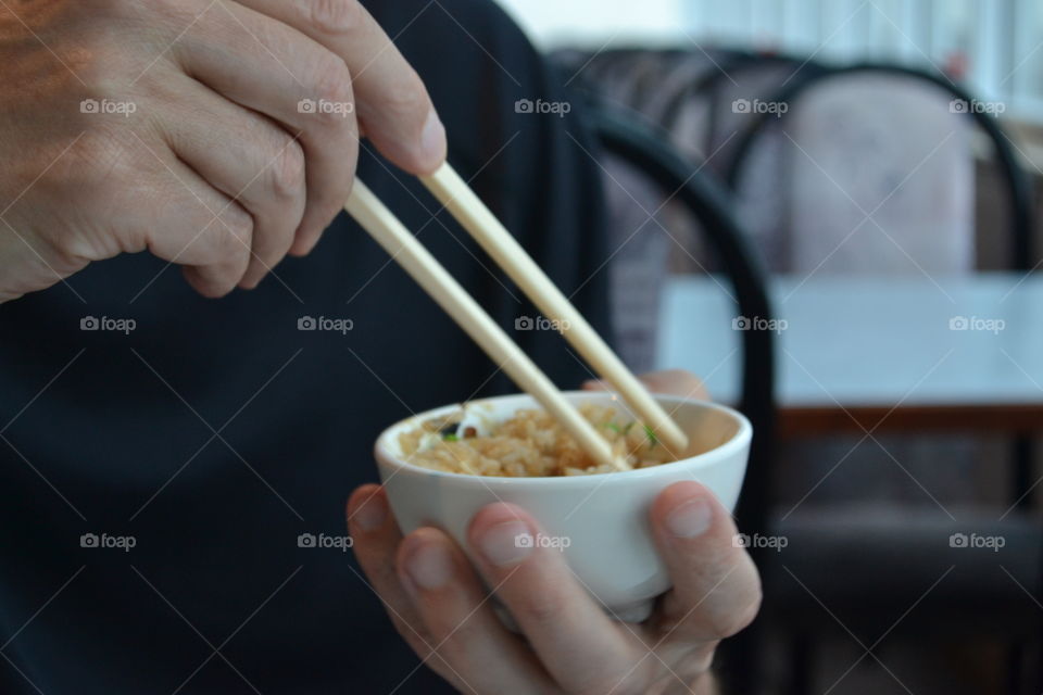 Man eating fried rice from small bowl