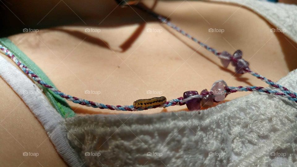 Catipillar crawling on a girls necklace
