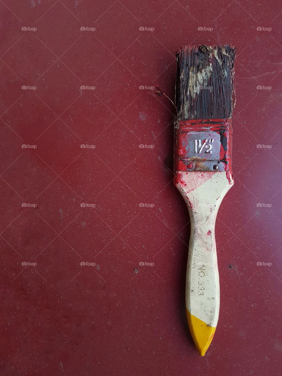 close up of brush with dry paint isolated on a red plain background surface