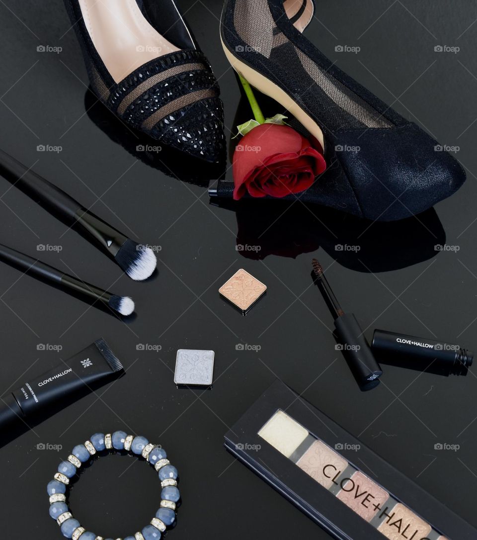 Still life flat lay with makeup and black dress heels