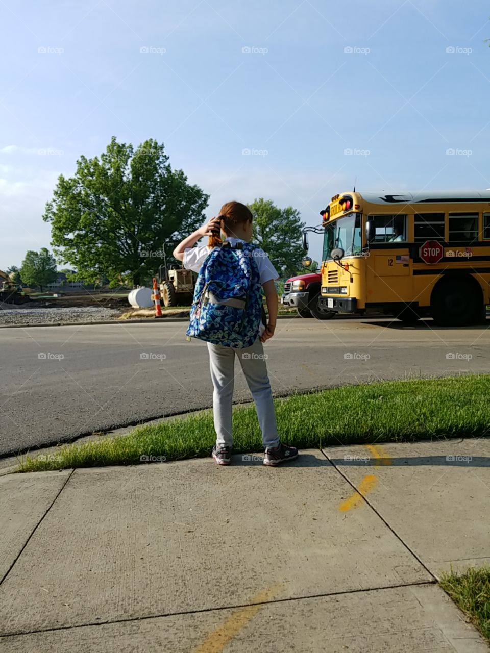 Little schoolgirl waiting at the bus stop