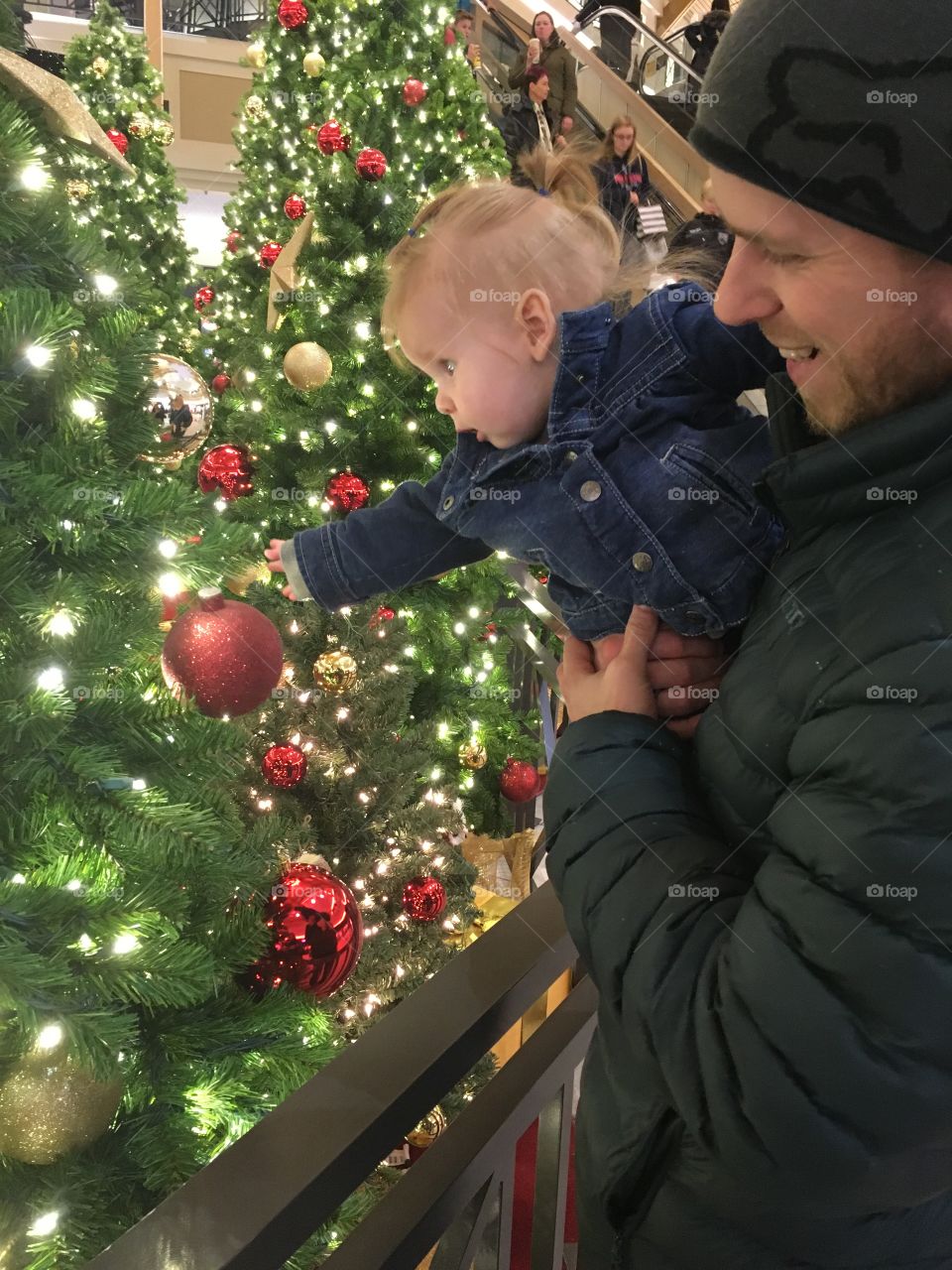 Father and daughter by Christmas trees