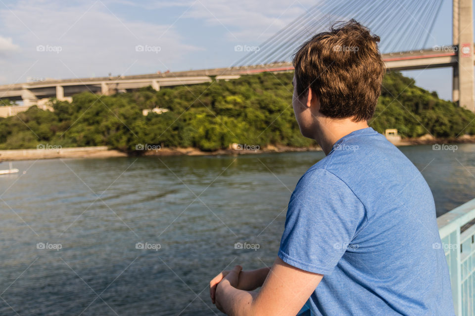A teenager watching a sea and a bridge