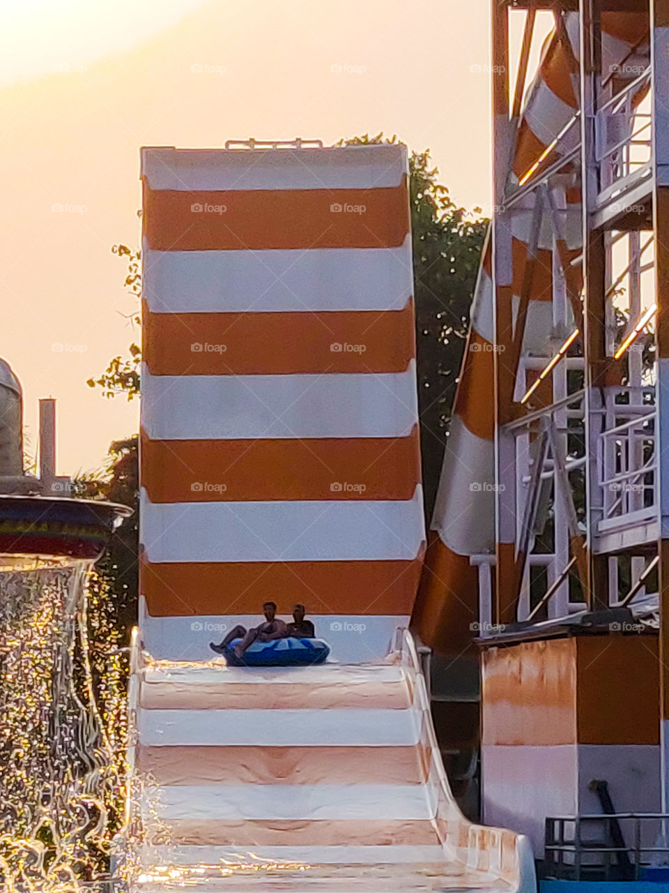 people enjoying rides in water park during golden hour in a hot summer day