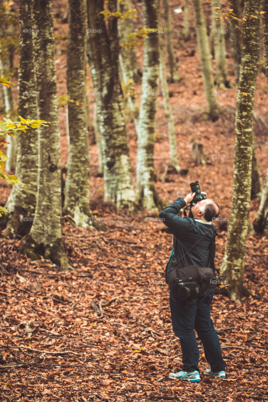 Man Photographer In Forest In Autumn Season
