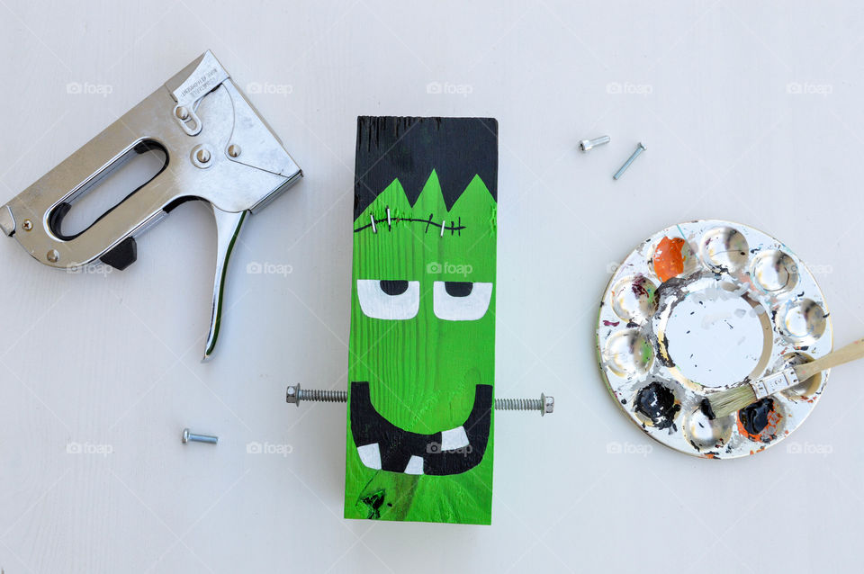 Building and painting a frankenstein out of a wooden block with paint, bolts and staple gun laid out