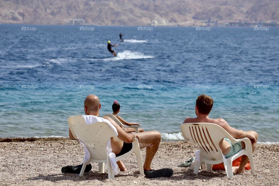 Two men sitting together on the beach