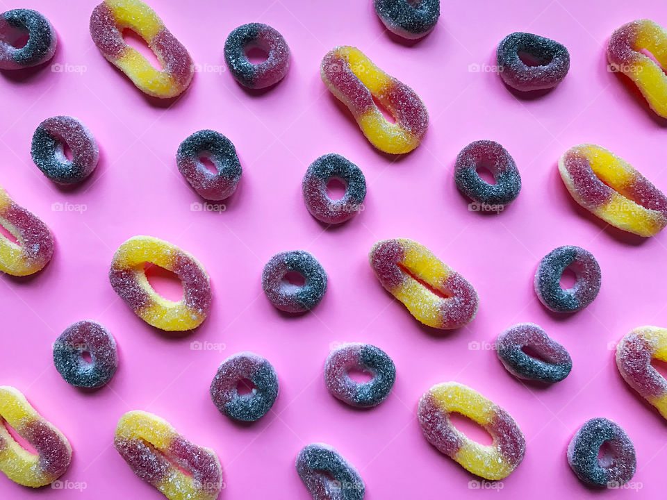 Flat lay pattern made of Colorful round rubber candies on pink pastel background 