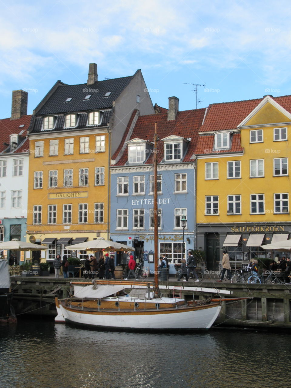 Copenhagen nyhvn with colourful buildings and sailboat with blue sky on a cold day