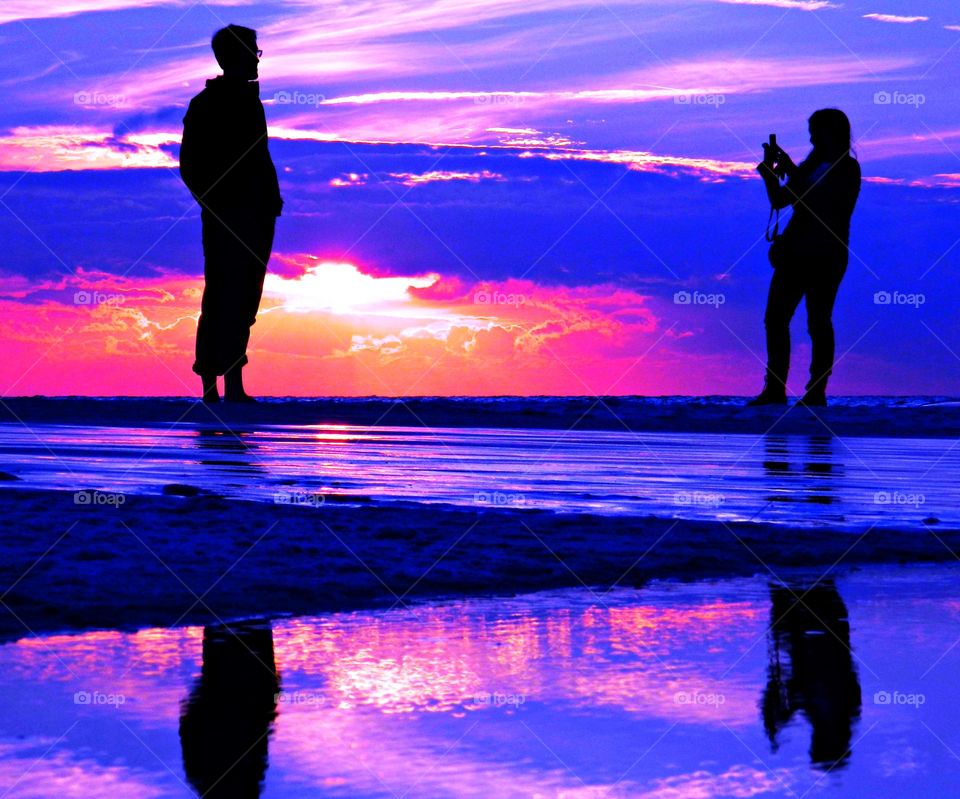 A Video Creator captures a man standing in the Gulf of Mexico during a colorful sunset