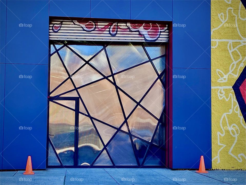 The inset aluminum covered doorway with the door on the far left is covered by a multifaceted angular pattern that mimics a spider web. 2023. Hypnotic Productions