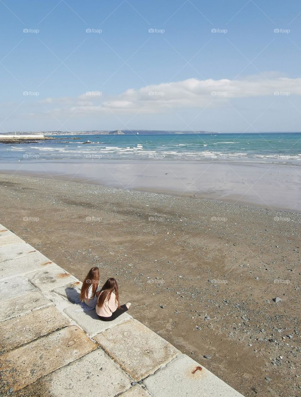 Two girls relax on the seashore. Nice weather. Spring time.