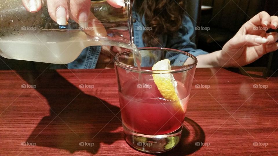 pouring lemonade over a red ice cube