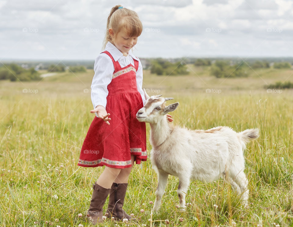 girl playing with a goat in the field