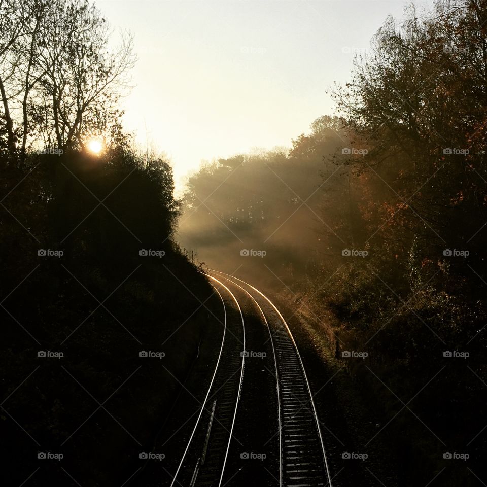 Misty, early morning railway lines, no people. Straight lines and some sun light 