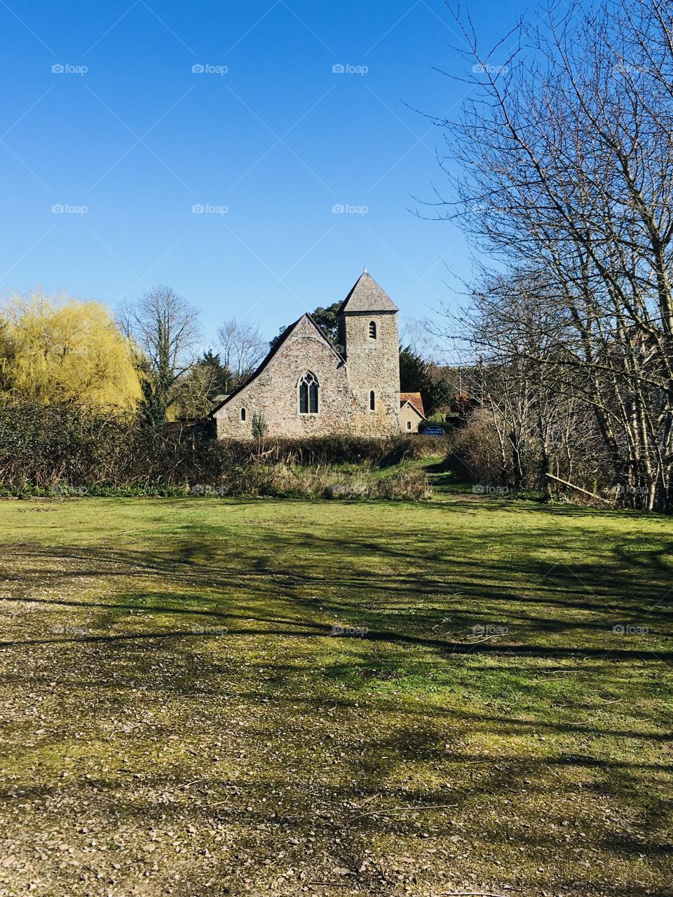 A beautiful long distance shot of a pretty village church. Gorgeous blue sky adding to the overall beauty of an idyllic scene.