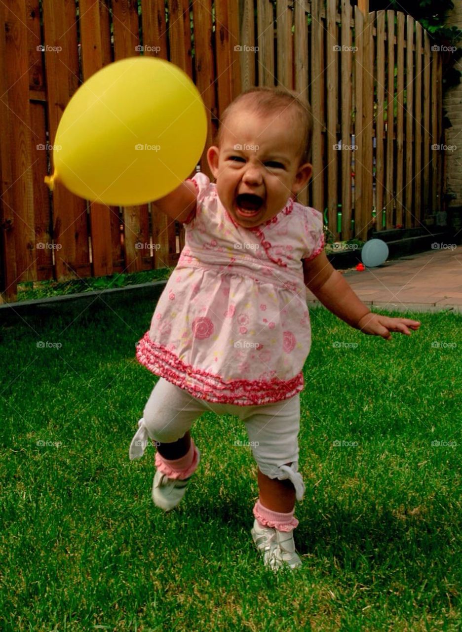 Baby girl yelling with her yellow balloon in her hand