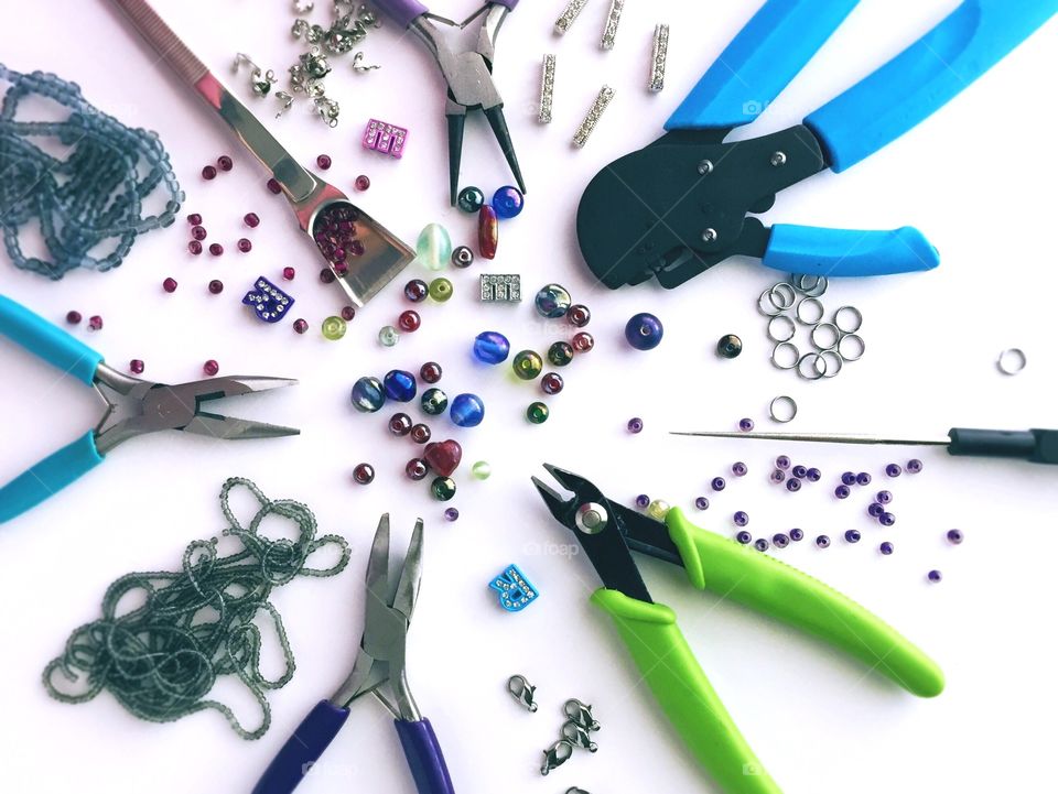 Pliers with bead necklace on white background