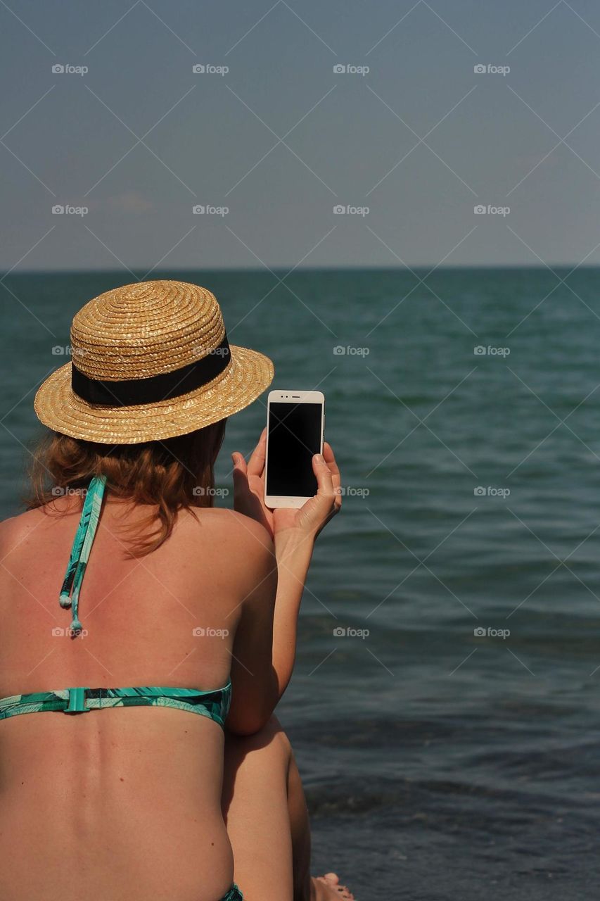 Girl with a phone on the shore of a salt lake