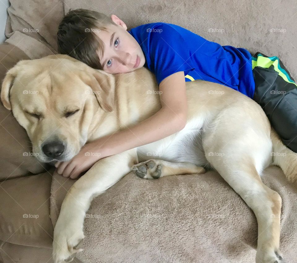 A boy resting with his yellow Labrador 