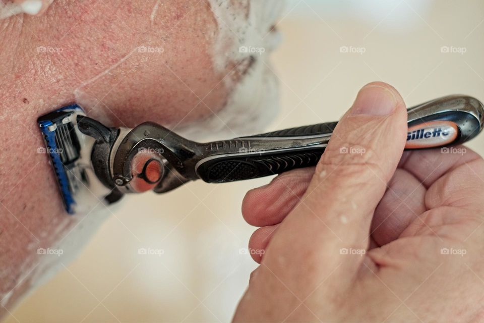 Man shaving his beard using a razor blade