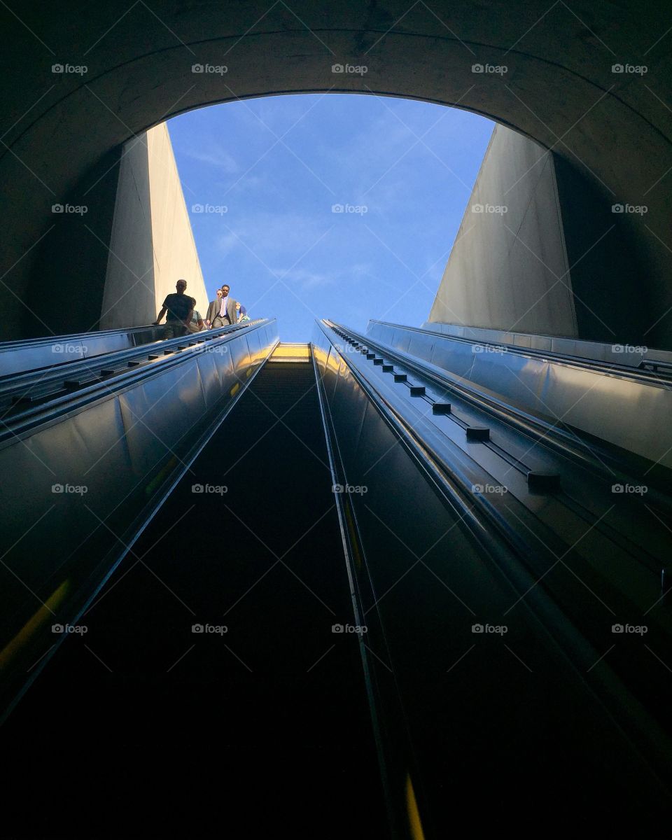 People on the tunnel escalator in a blue sky day