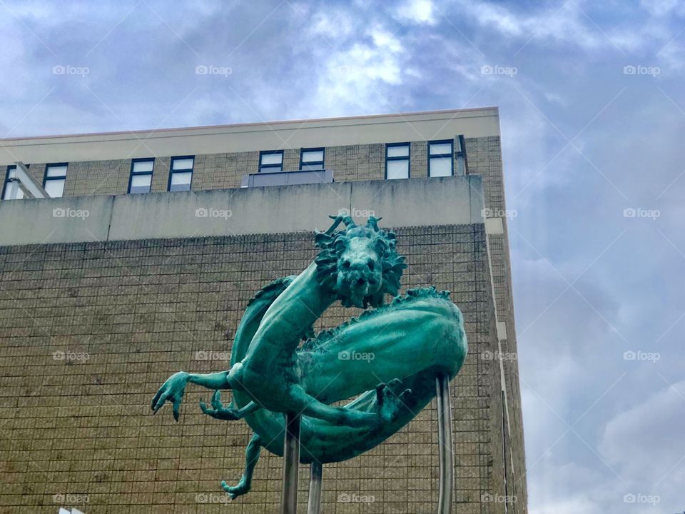 Dragon sculpture seen from below against a building backdrop and dark cloudy sky in Chinatown, Philadelphia, Pennsylvania.