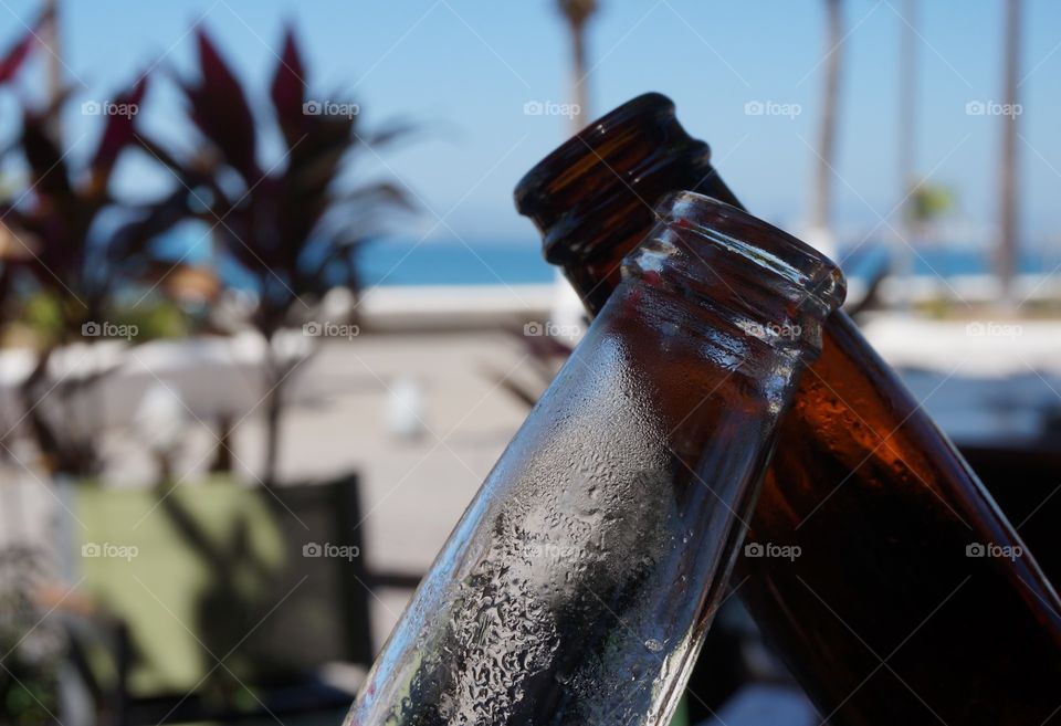 Cheers!!!  Clinking ice cold beer bottles in a toast.  Photo taken at restaurant by the beach on Mazatlan, Mexico.