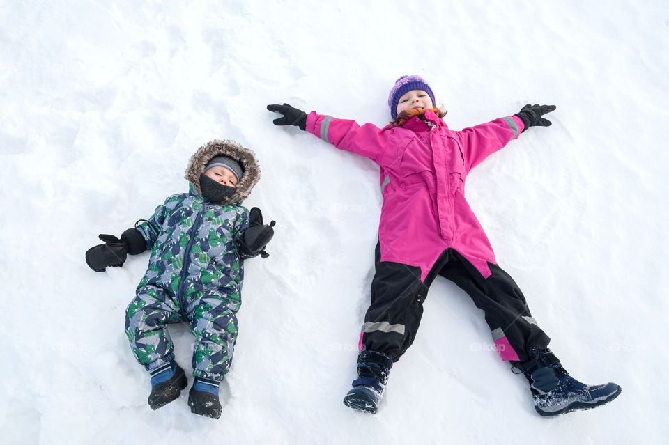 Wintertime. Children enjoying lying down on snow.