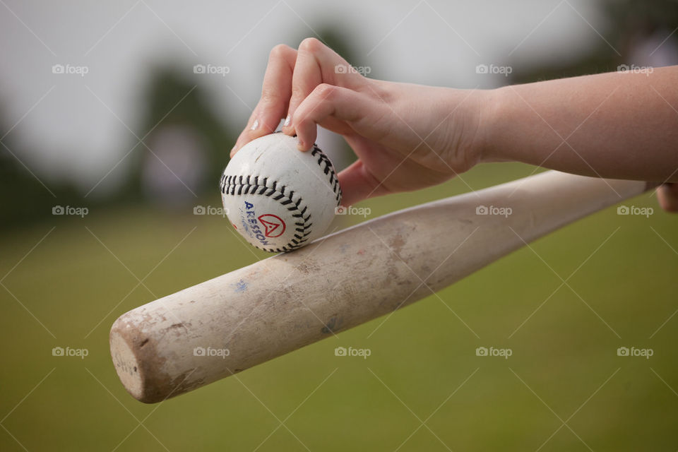 Hand holding a rounders bat and ball close up