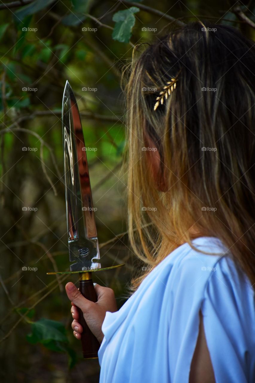 girl looking herself in a dagger