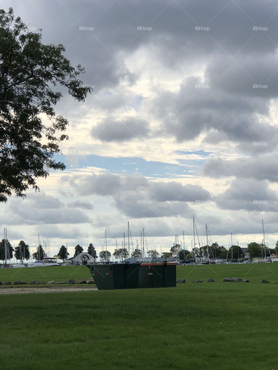 Sky, trees, grass, sailboats and a dumpster....