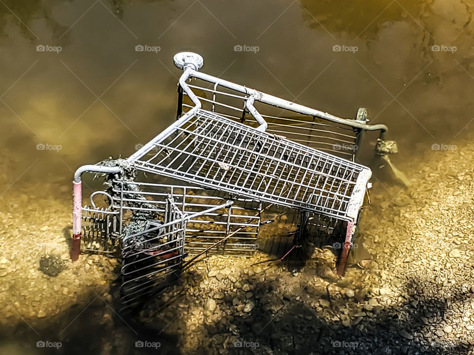 Abstract:  grocery basket sideways in dirty brown water