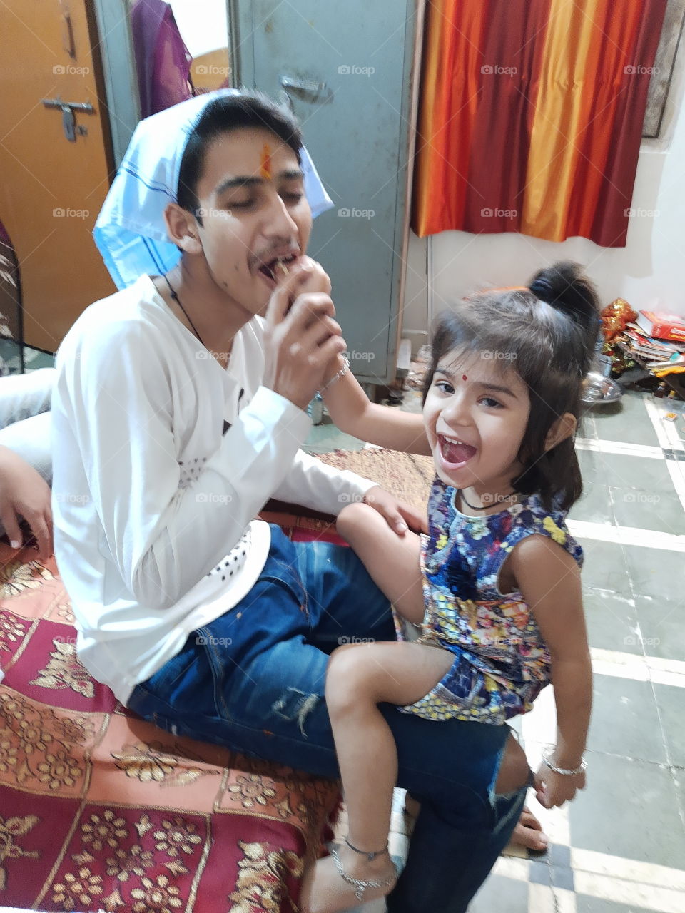 On the occasion of the Indian festival of Bhai Dooj , baby is feeding her brother sweets but has also kept her mouth open.