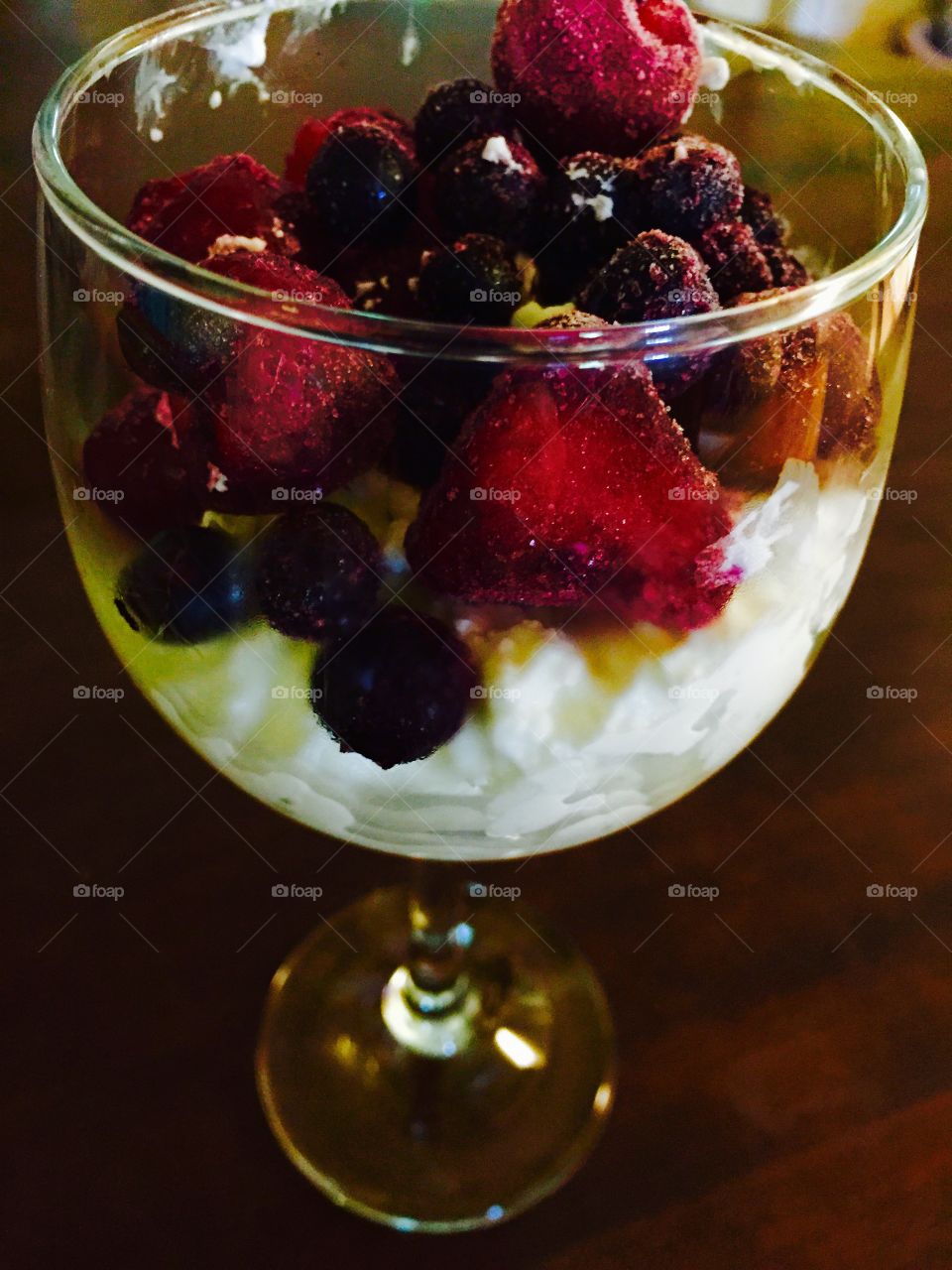 Cottage cheese, blueberries, strawberries, cherries in a dessert glass, looking colorful.