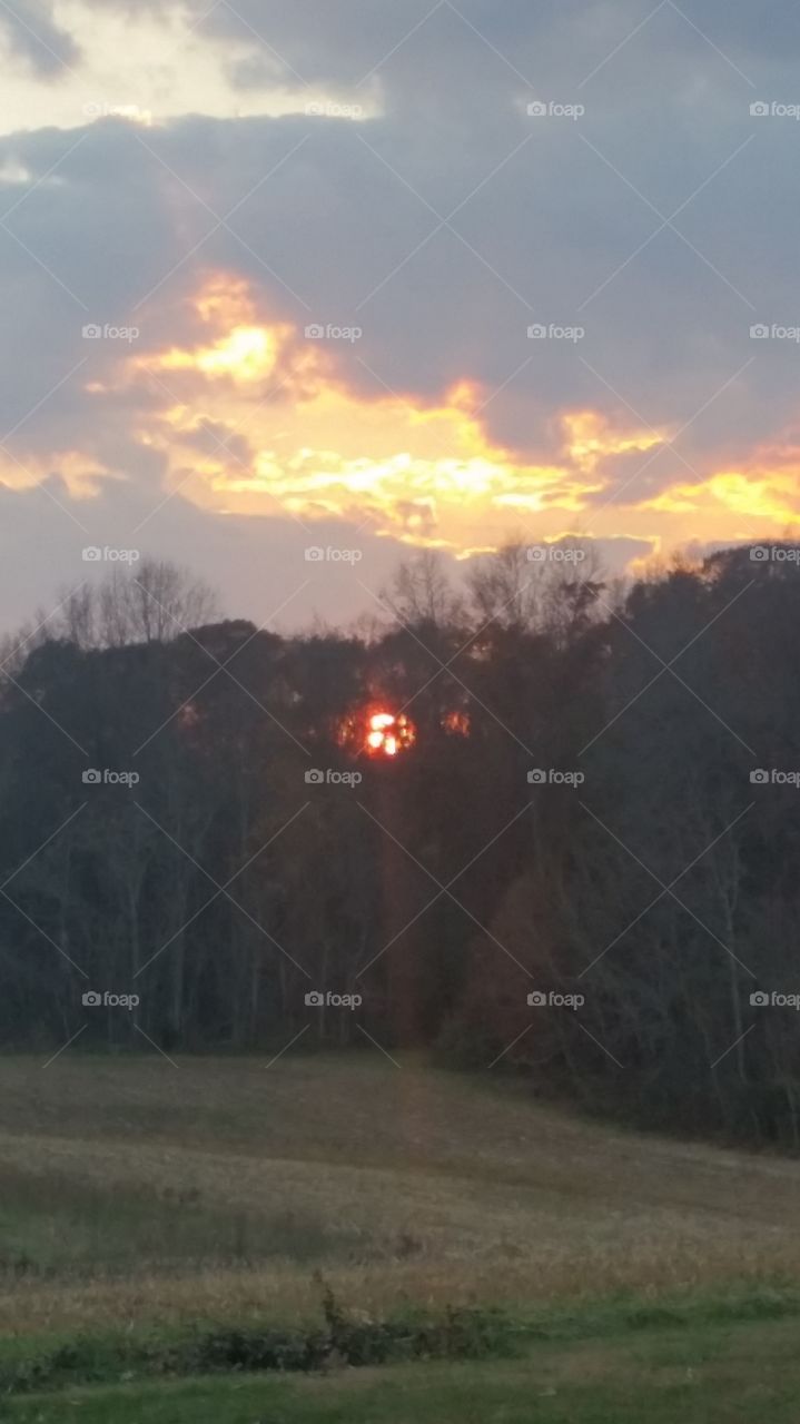 great view of a sunset over a field in the country during fall season