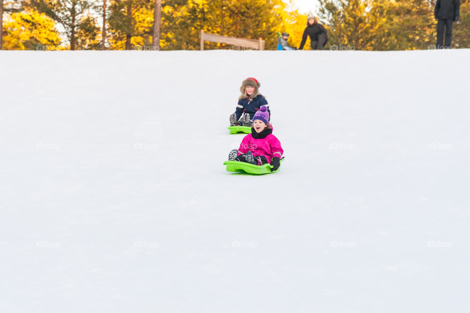 Kids sledging downhill.