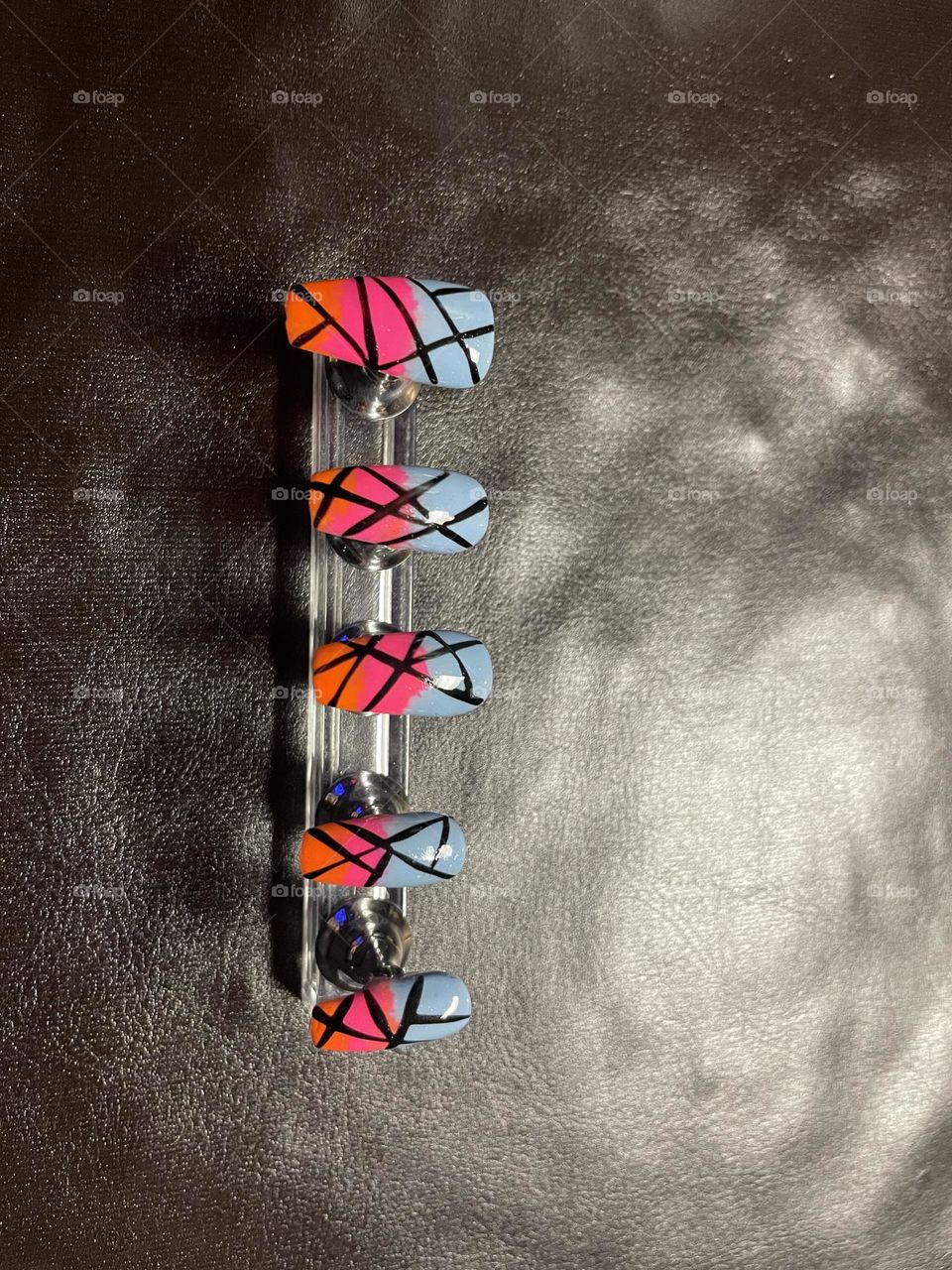 Orange, pink, and blue gel polish set of nails.