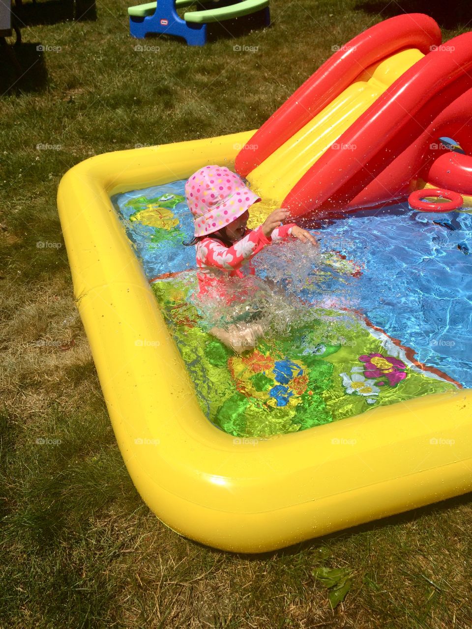 Little girl splashing around in a kiddie pool