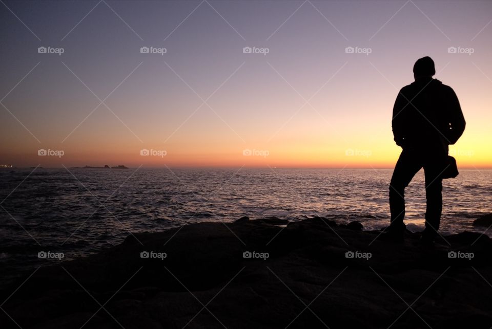 Shadow of man looks at the sea at sunset