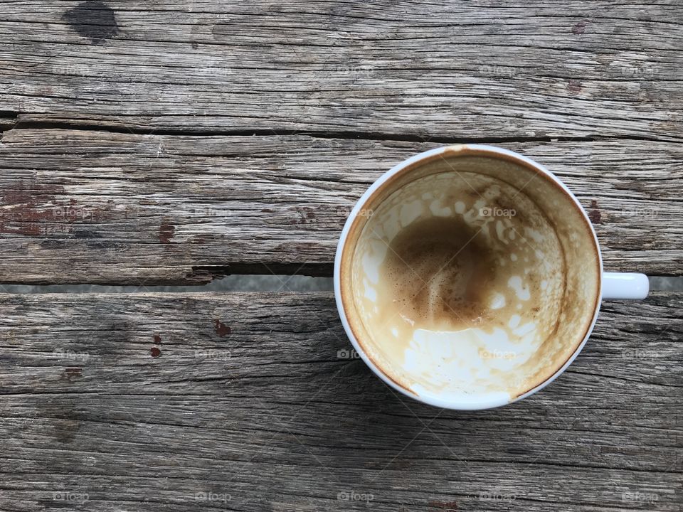 finished cup of hot cappuccino coffee, put on natural old brown wooden table in cafe, “coffee lover” concept