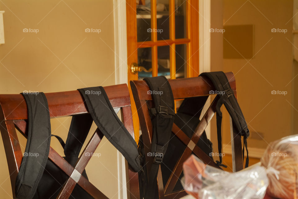 School is back in session, and two bookbags hang on the back of two chairs at kitchen table.
