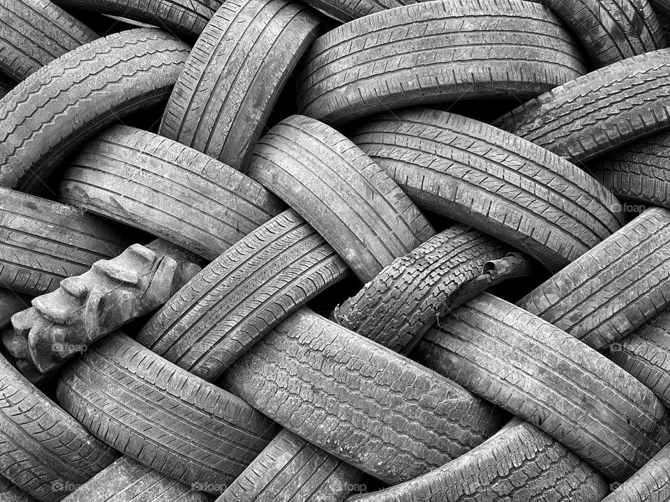 Pile of old automobile tires in a junkyard that create a basket weave pattern